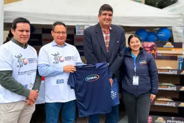 Representantes de Exibal durante evento de inocuidad alimentaria entregando camiseta institucional en feria agroindustrial