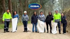 Equipo de colaboradores de EXIBAL realizando jornada de limpieza y reforestación en un entorno forestal, recogiendo residuos con sacos en un camino de tierra.