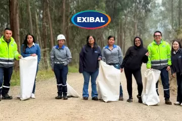 Equipo de colaboradores de EXIBAL realizando jornada de limpieza y reforestación en un entorno forestal, recogiendo residuos con sacos en un camino de tierra.