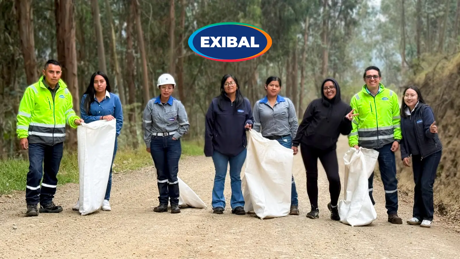 Equipo de colaboradores de EXIBAL realizando jornada de limpieza y reforestación en un entorno forestal, recogiendo residuos con sacos en un camino de tierra.
