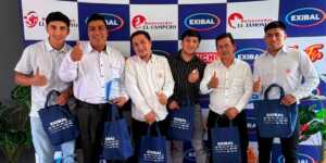 Grupo de colaboradores de Exibal sonriendo y sosteniendo bolsas promocionales en un evento corporativo