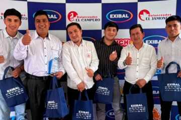Grupo de colaboradores de Exibal sonriendo y sosteniendo bolsas promocionales en un evento corporativo