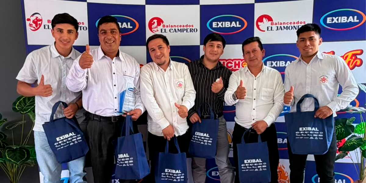 Grupo de colaboradores de Exibal sonriendo y sosteniendo bolsas promocionales en un evento corporativo
